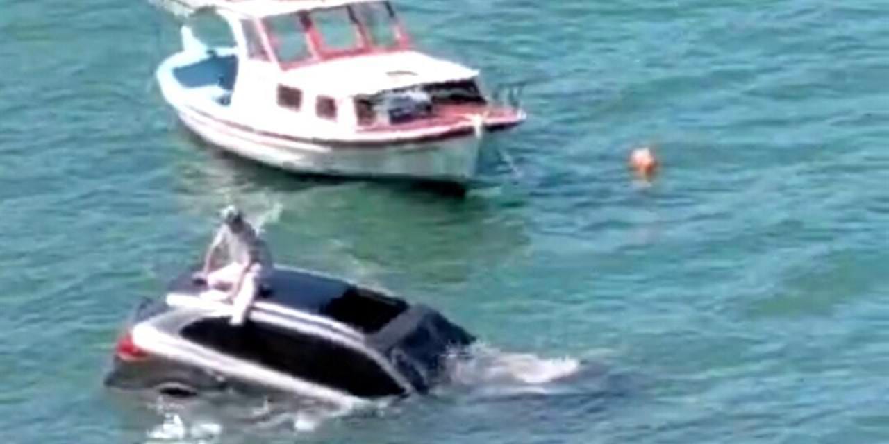 Denize uçan otomobilinin üzerinde oturup yardım bekledi